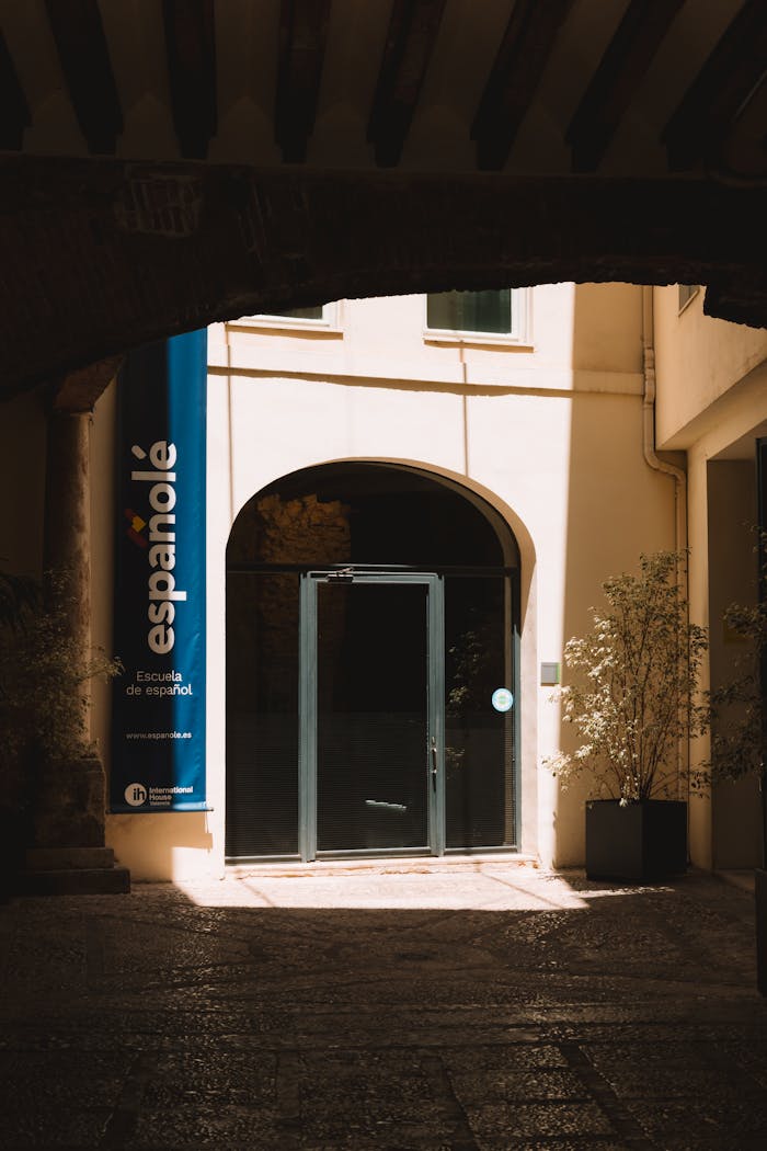 why-choose-us Arched entrance to a Spanish language school in Valencia, Spain, bathed in sunlight.