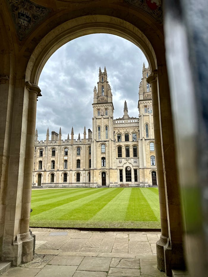 our-experience View of the historic All Souls College at Oxford University framed by an archway, perfect for educational and travel themes.