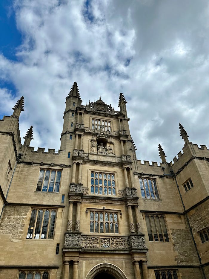 gallery-5 Majestic view of the Bodleian Library's Gothic architecture at Oxford University under a cloudy sky.