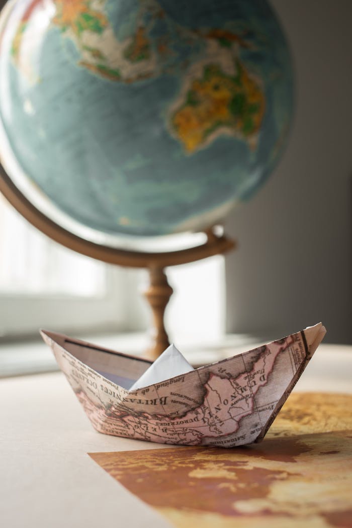Mastering the First Impression: Your intriguing post title goes here An origami boat made from a map rests near a globe, symbolizing global travel and exploration.